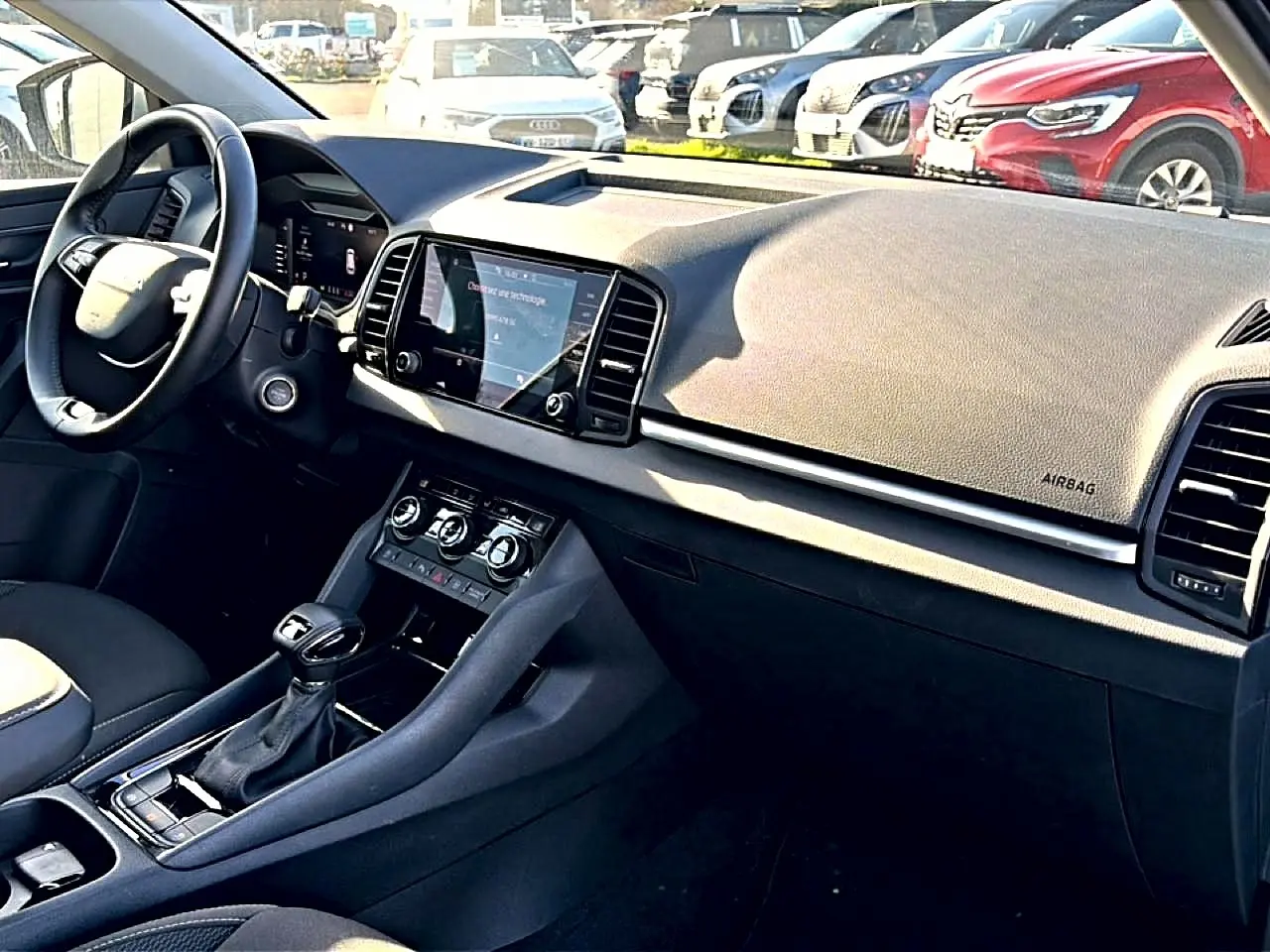 Vue intérieure côté conducteur du tableau de bord noir du Skoda Karoq 1.5 TSI 2025 avec écran tactile central et volant cuir.