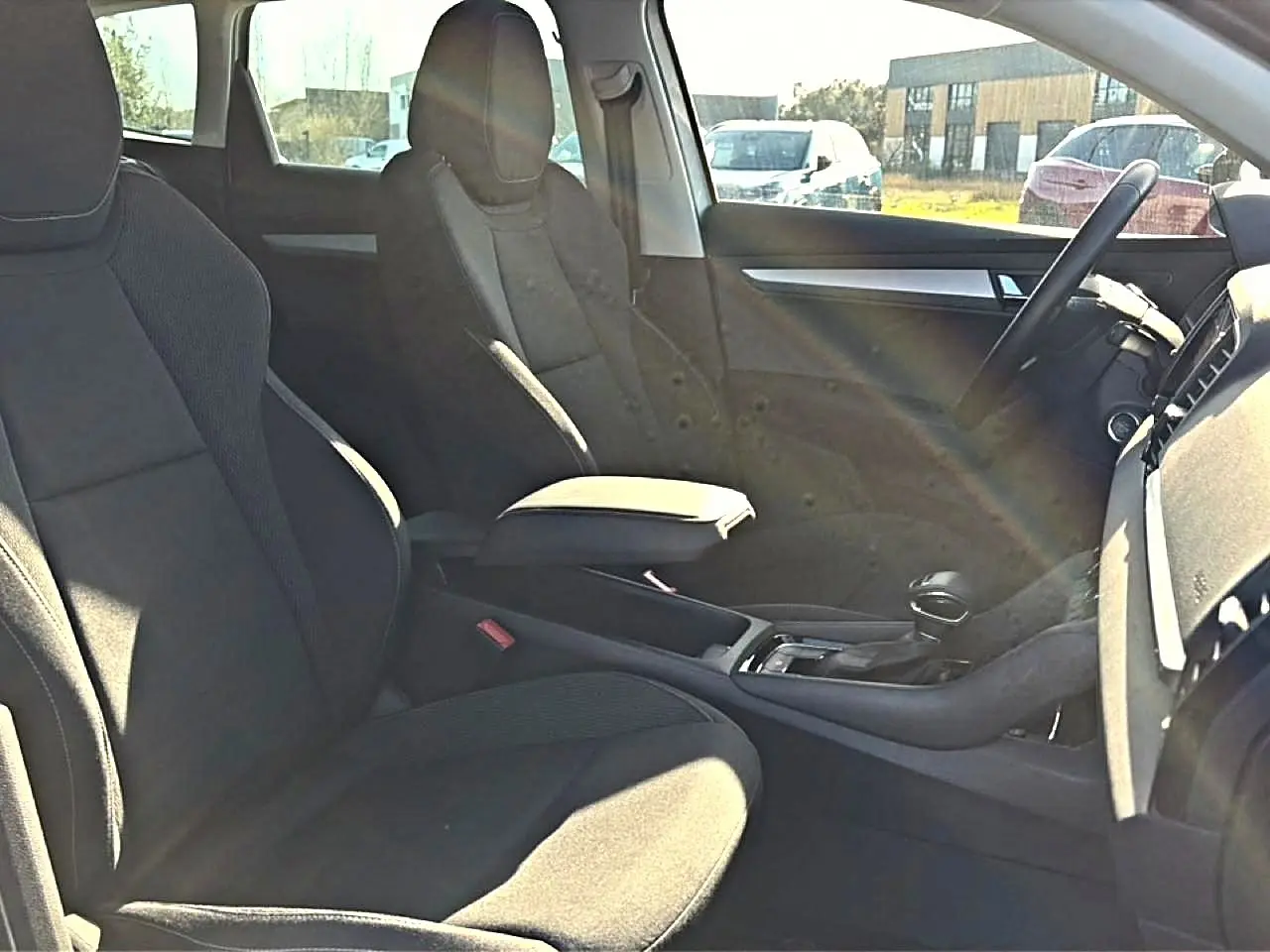 Vue intérieure côté droit du Skoda Karoq 2025, sièges tissu gris et accoudoir central avec rangement.