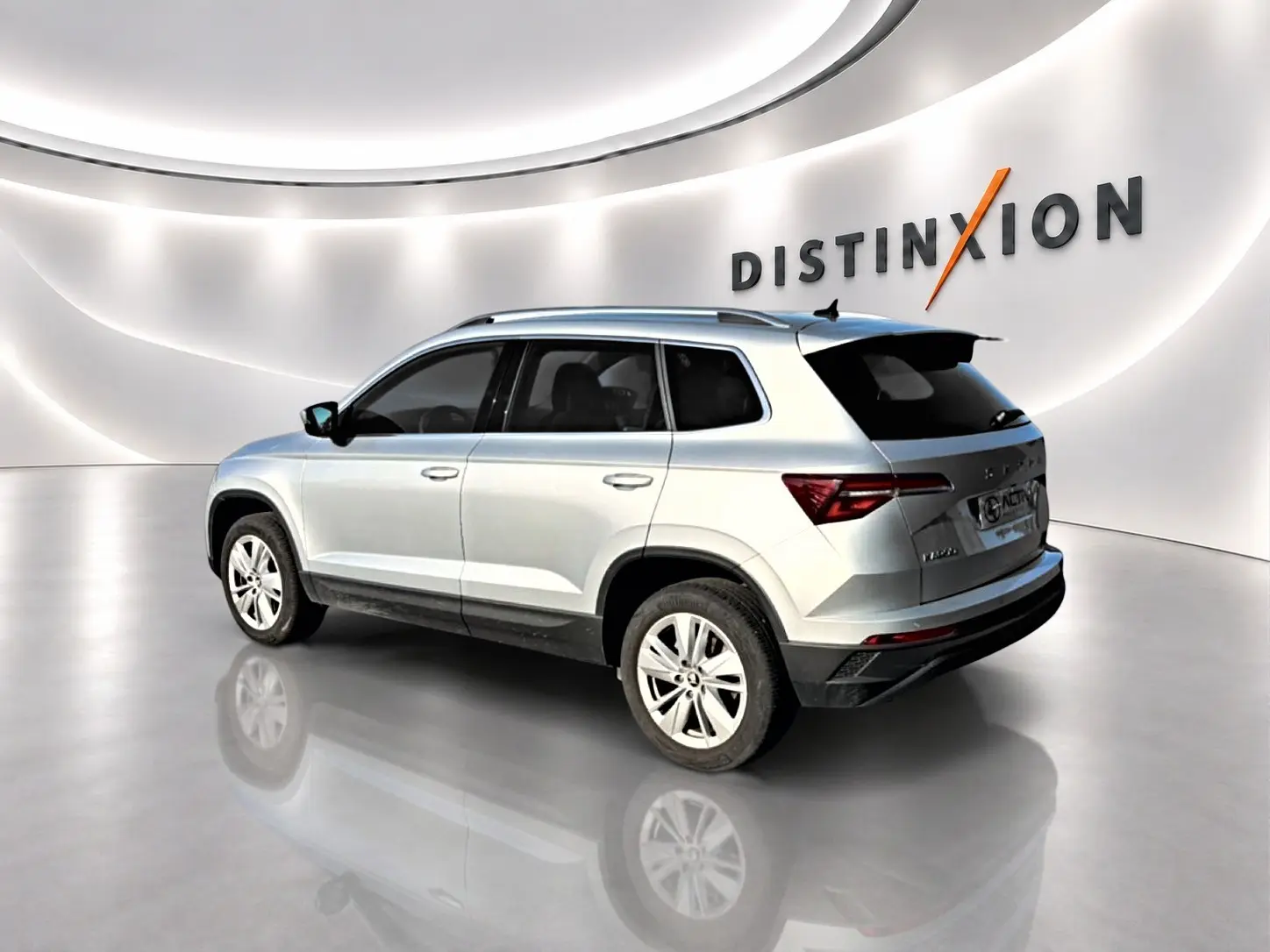 Vue 3/4 arrière droite d'un Skoda Karoq gris métallisé dans un showroom lumineux avec jantes alu.