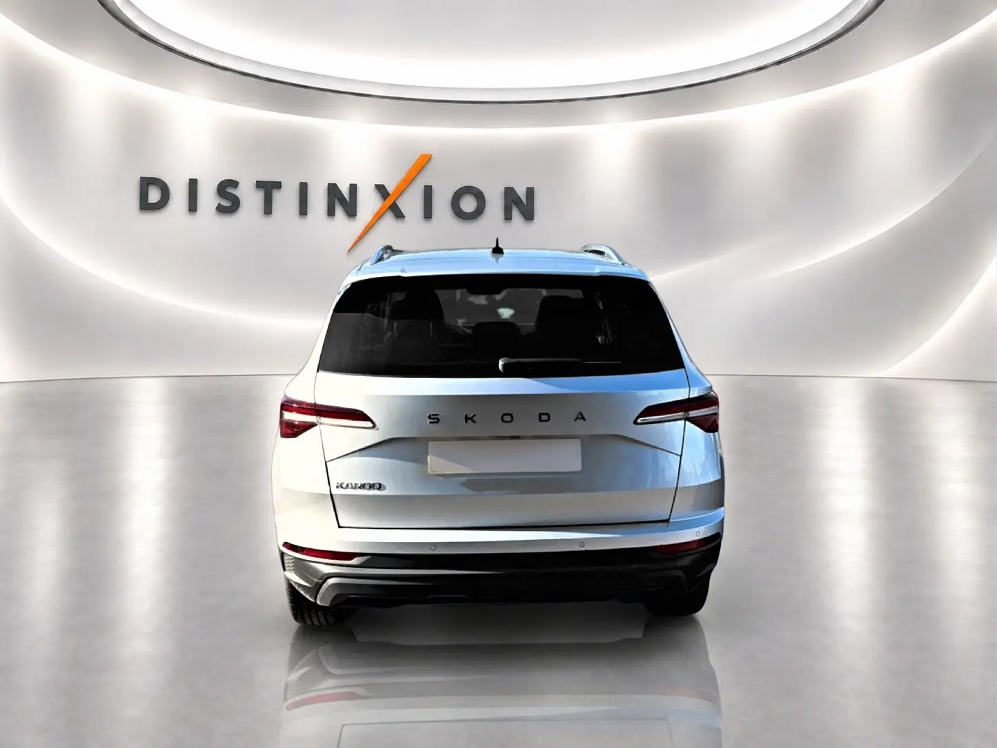Vue arrière d'un Skoda Karoq gris 2025 dans un showroom avec logo Distinxion en arrière-plan.