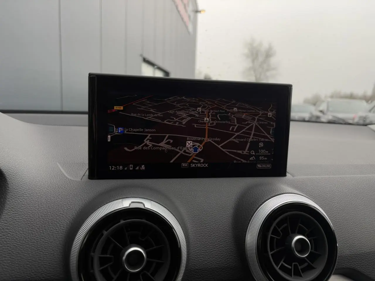 Vue intérieure du tableau de bord de l'Audi Q2 30 TFSI S-Line 2024, écran de navigation et aérateurs ronds noirs.