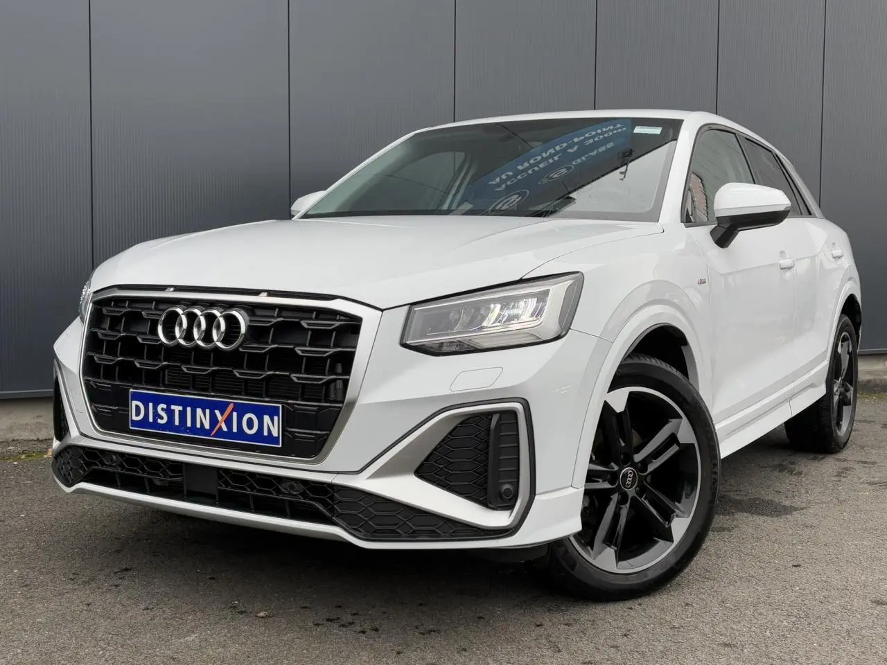 Audi Q2 30 TFSI S-Line blanc Glacier en 3/4 avant droit, avec calandre noire et jantes alliage noires polies.