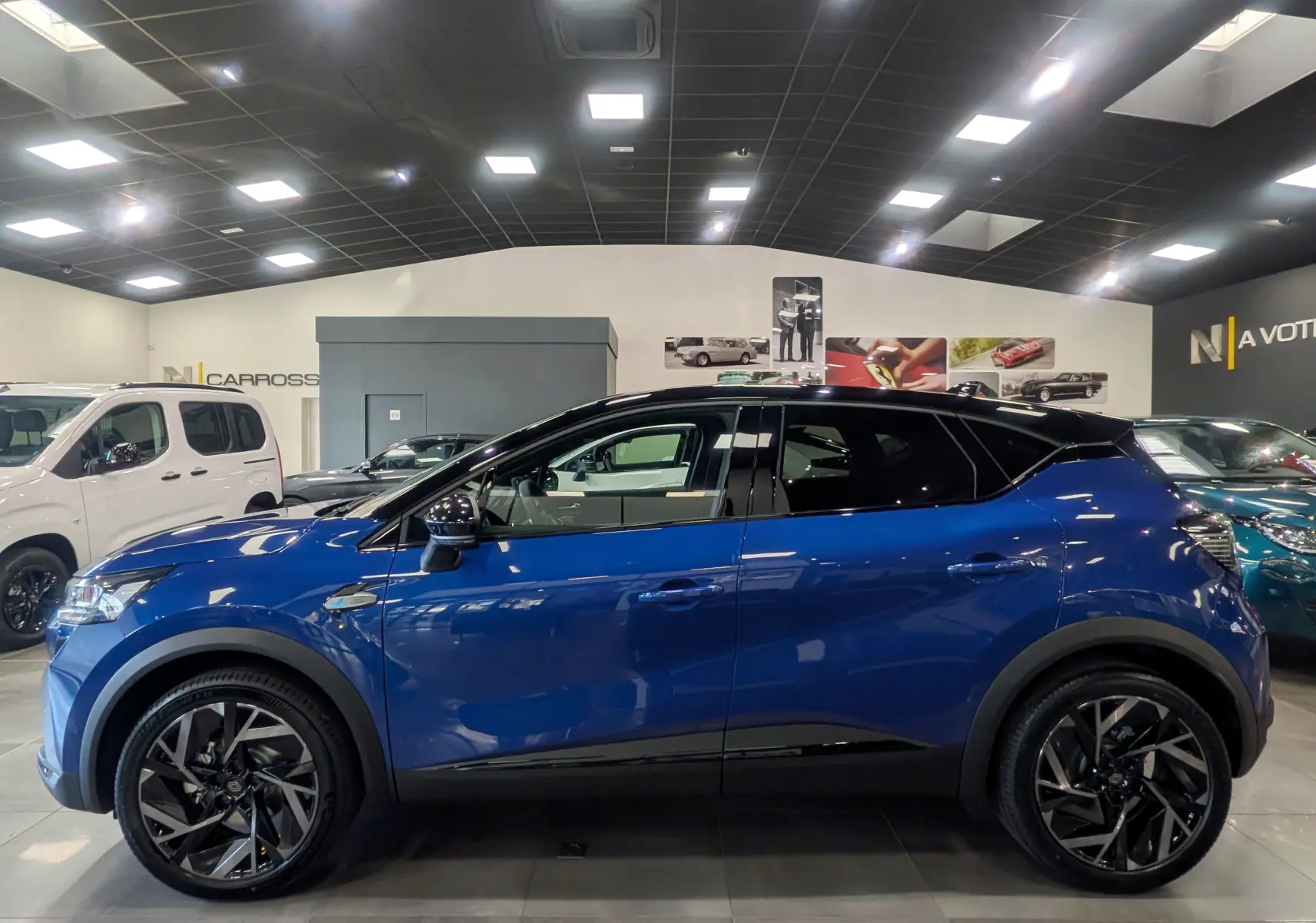 Profil côté gauche du Renault Captur E-TECH Full Hybrid 160 CH esprit Alpine bleu Iron avec toit noir en showroom.