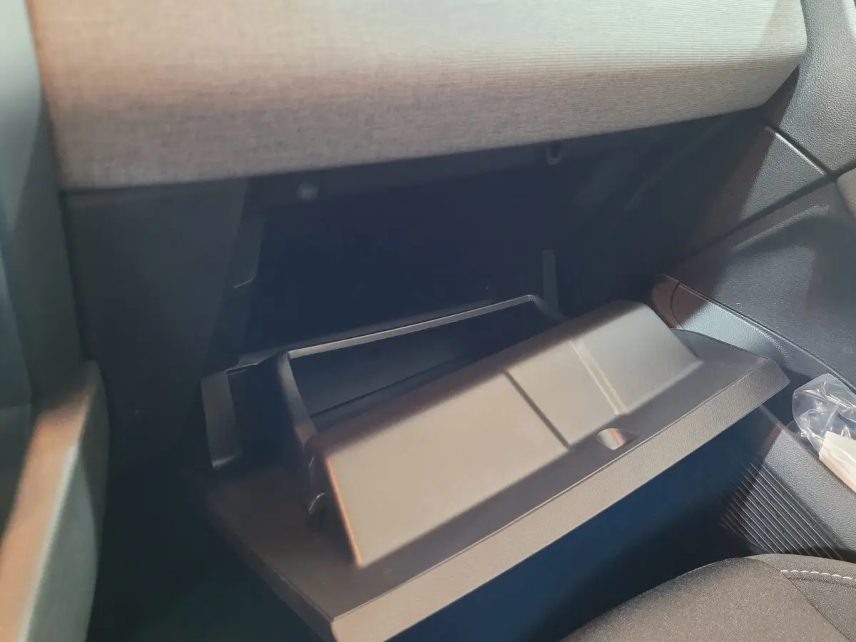 Gros plan sur la boîte à gants ouverte de la Renault Clio gris foncé, montrant l'intérieur du rangement passager.