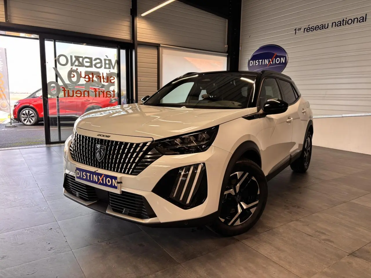 Peugeot 2008 blanc vue 3/4 avant droit en intérieur, avec calandre verticale et jantes noires distinctives.