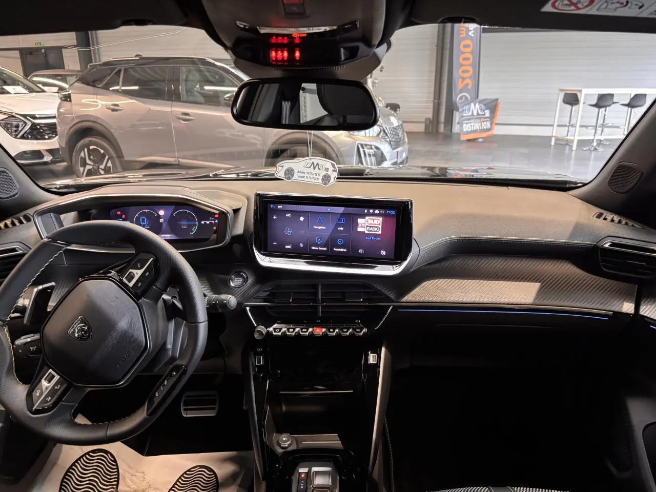 Vue intérieure avant du Peugeot 2008 blanc 2025, mettant en valeur le tableau de bord numérique et l'écran tactile central.