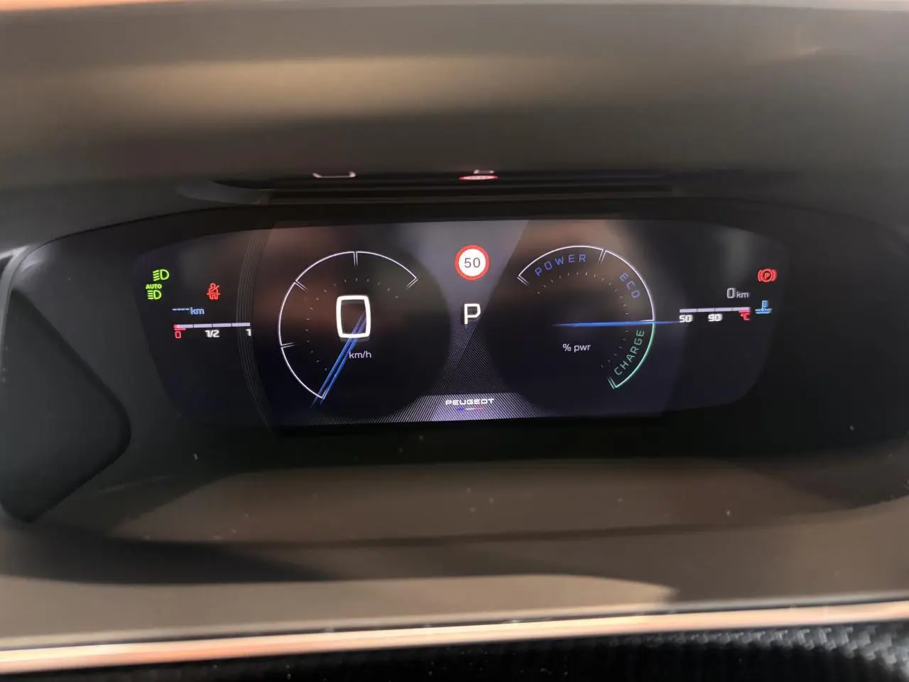 Tableau de bord numérique du Peugeot 2008 blanc 2025, affichant la vitesse à 0 km/h et indicateurs hybrides.