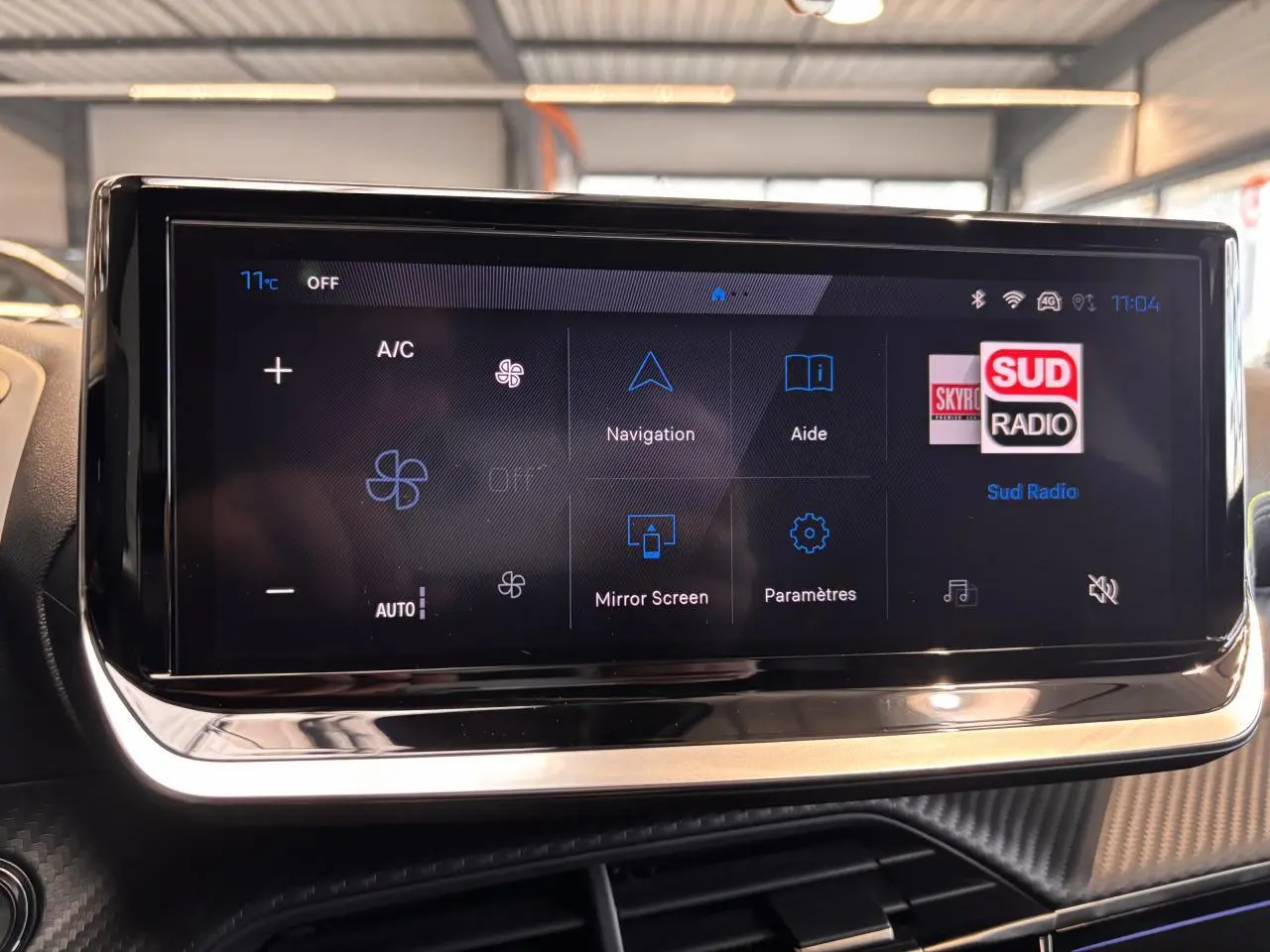 Écran tactile central du Peugeot 2008 blanc 2025 affichant les options de climatisation et navigation en intérieur.