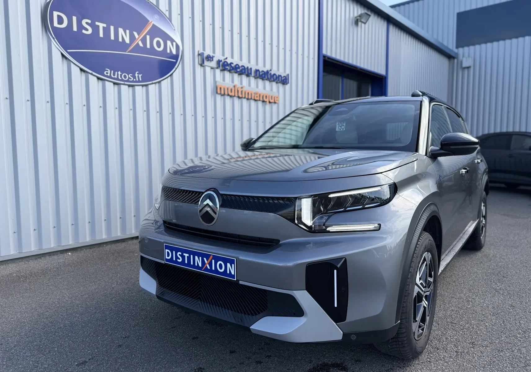 Vue 3/4 avant droite d'une Citroën C3 Aircross électrique gris Mercury avec toit noir et signature lumineuse LED.