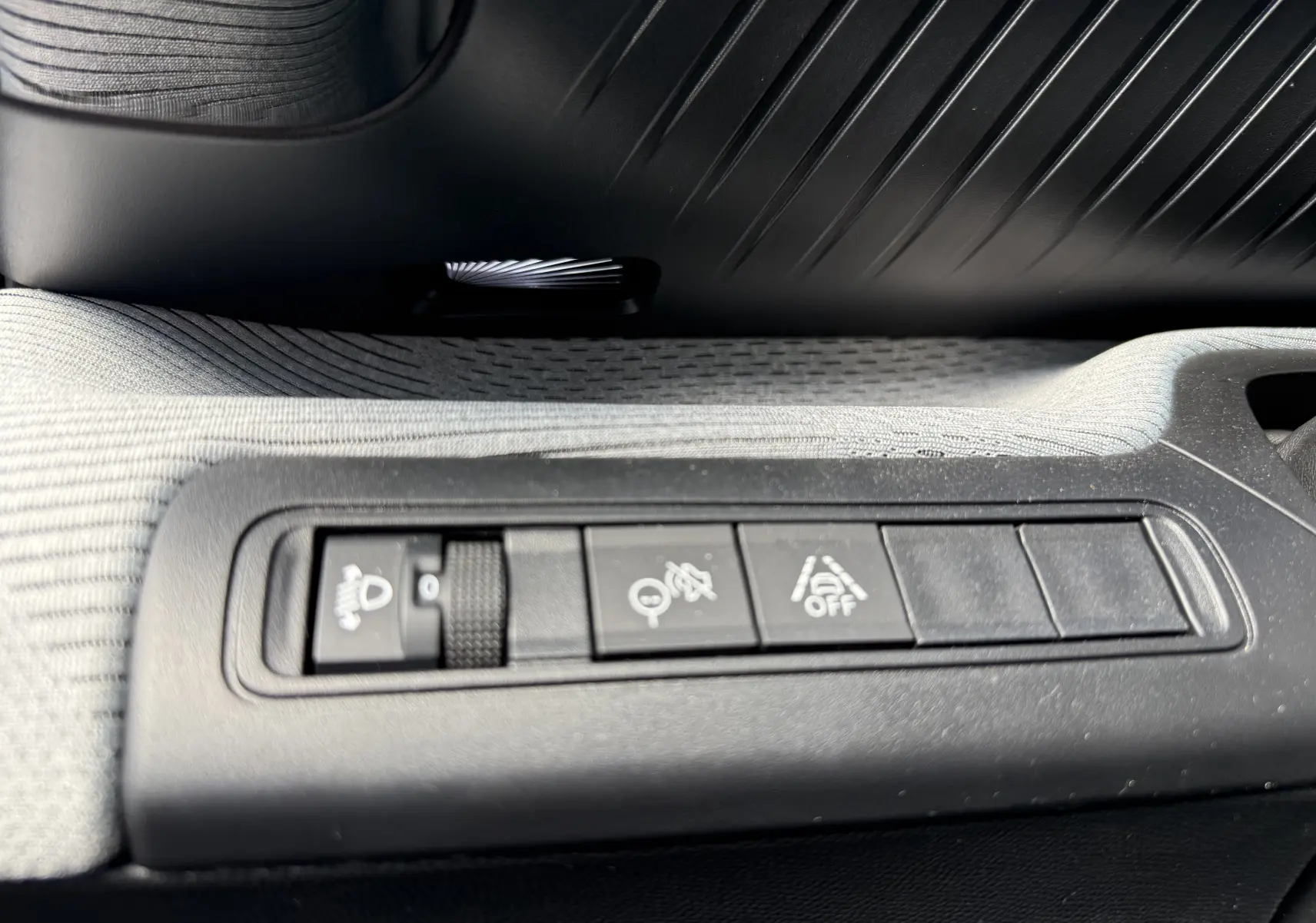 Détail intérieur montrant les commandes de réglage des phares et aides à la conduite sur la porte côté gauche du Citroën C3 Aircross gris Mercury.