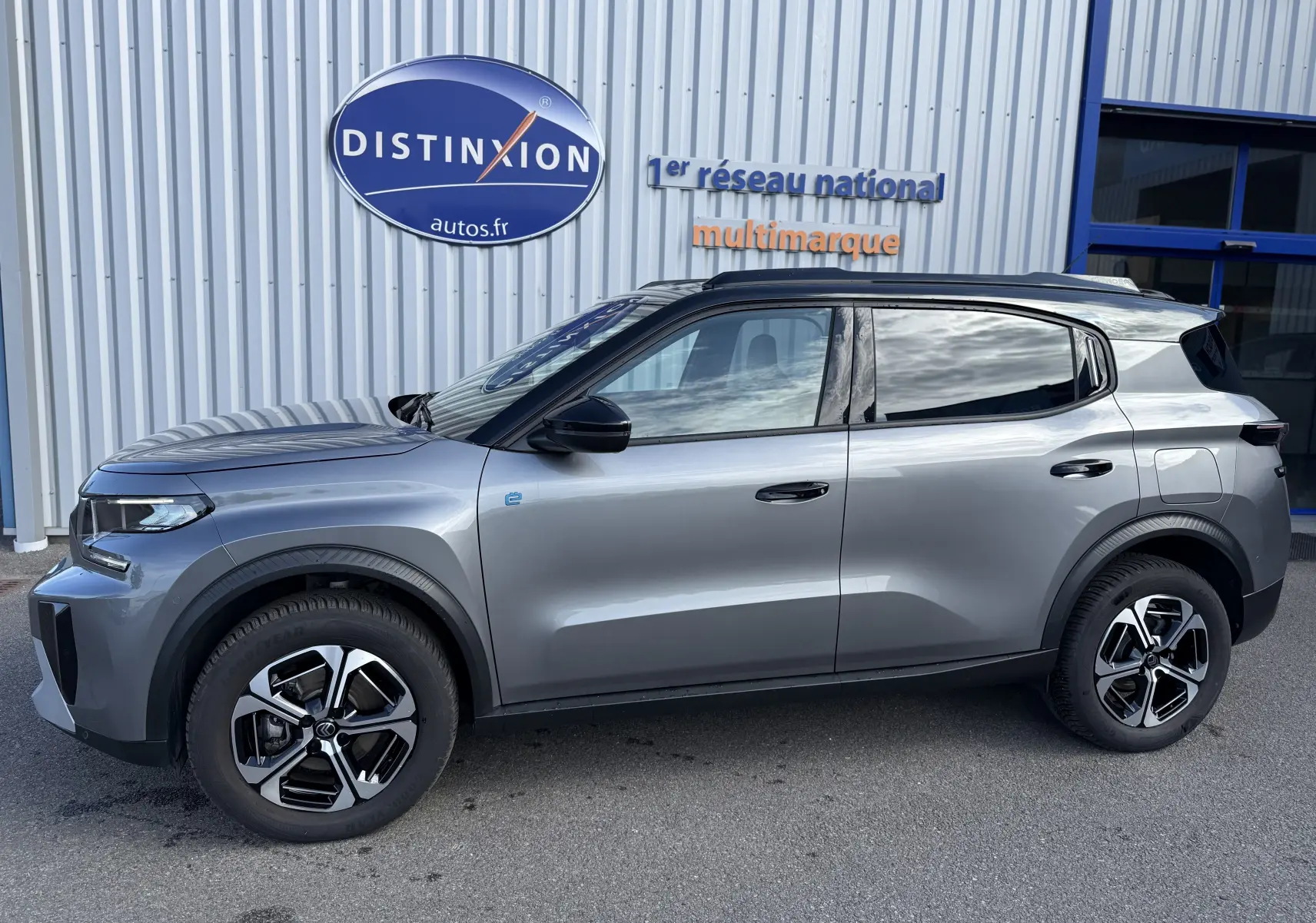 Vue de profil côté gauche d'une Citroën C3 Aircross électrique 2025 gris Mercury avec toit noir et jantes bi-ton.