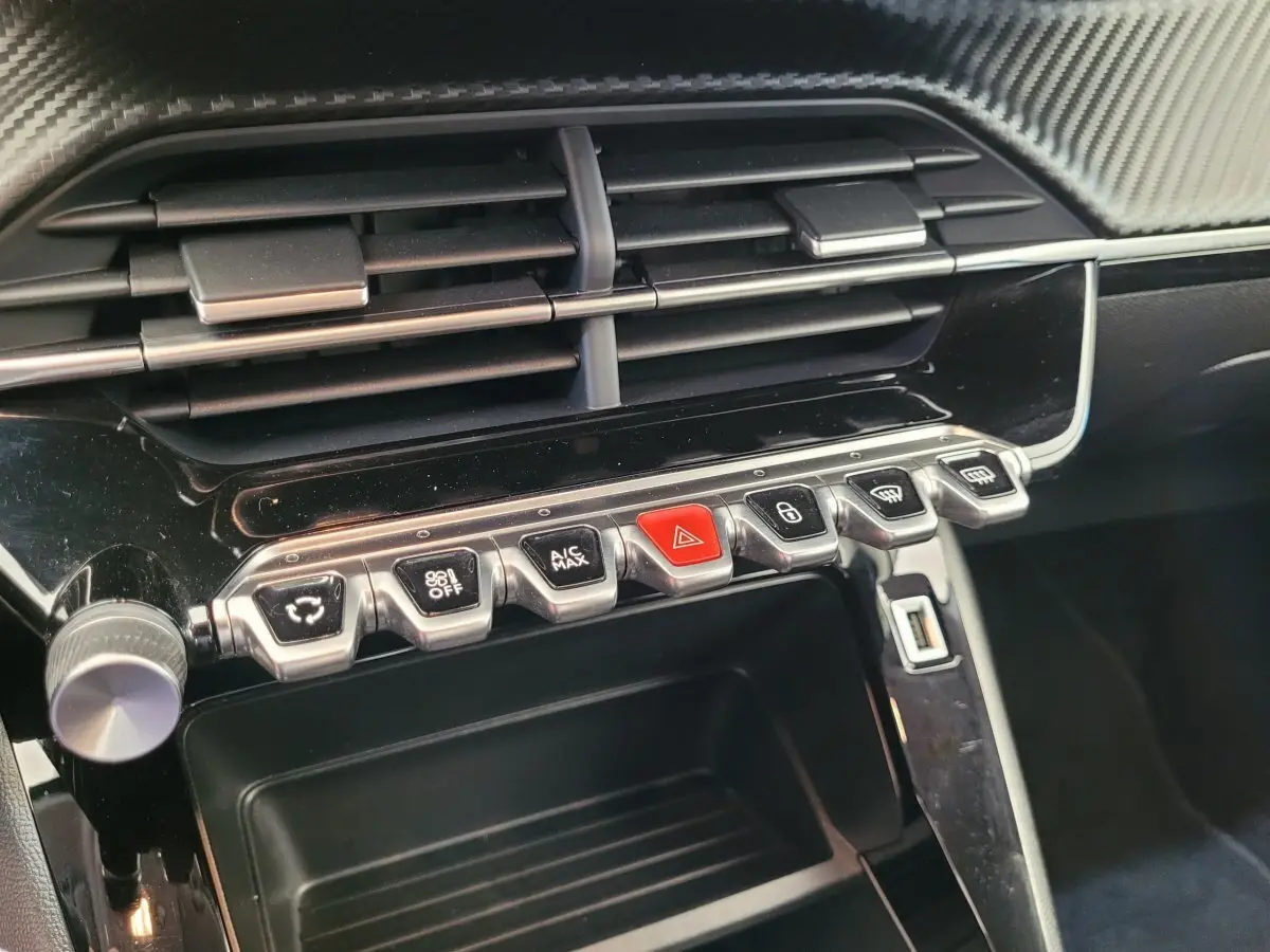 Gros plan sur la console centrale noire de la Peugeot 208 2023 avec boutons de commande et prise USB visible.