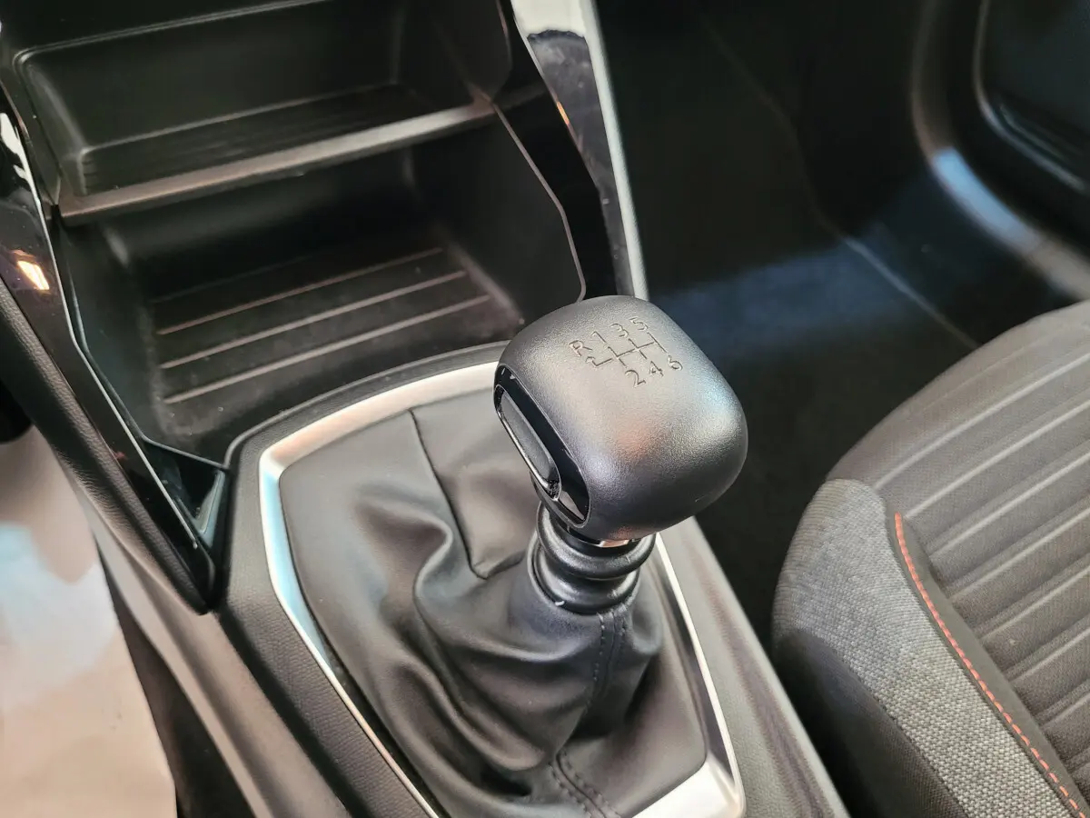 Le levier de vitesses manuel noir de la Peugeot 208 gris foncé, vu en gros plan côté passager.