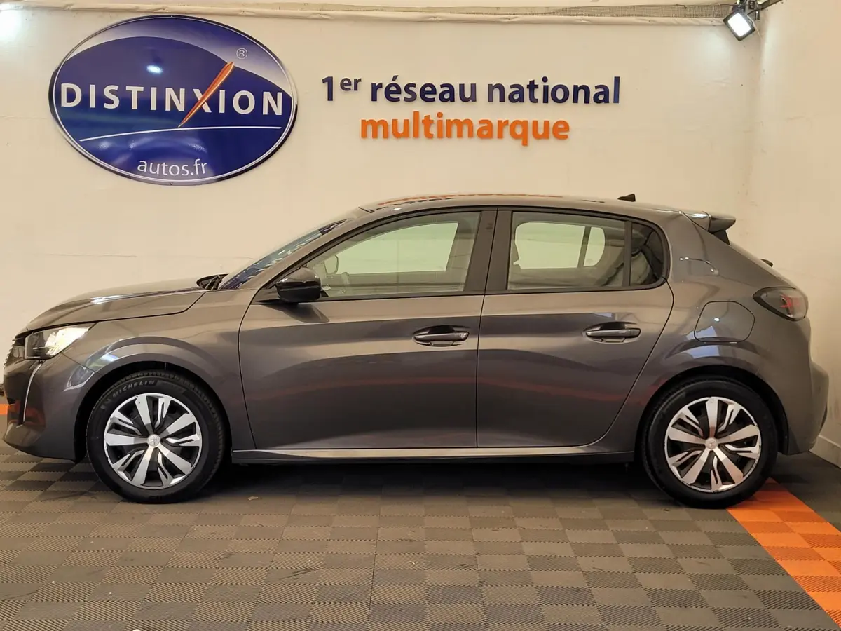 Profil latéral droit d'une Peugeot 208 BlueHDi 100 S&S Active Pack gris foncé stationnée en intérieur.