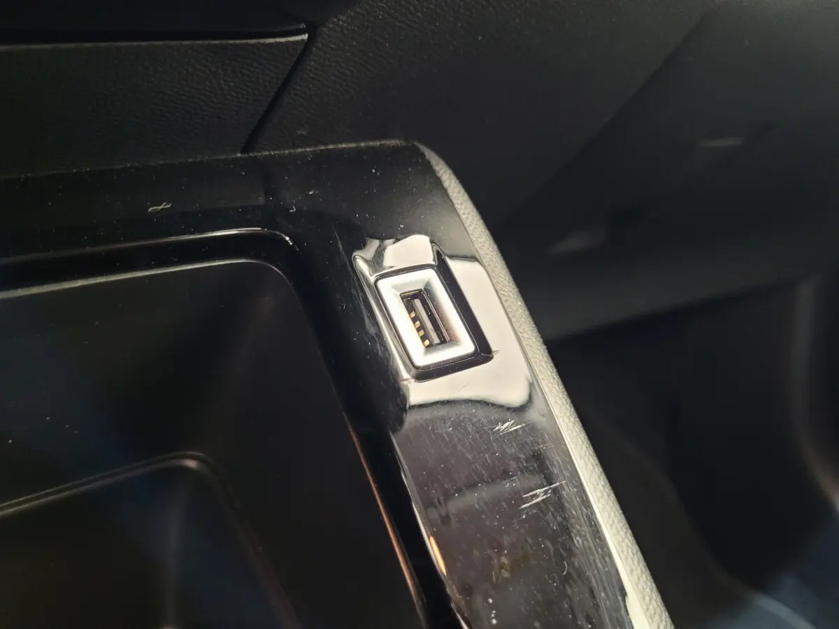 Gros plan sur un port USB intégré dans la console centrale noire d'un Peugeot 208 gris foncé 2023.