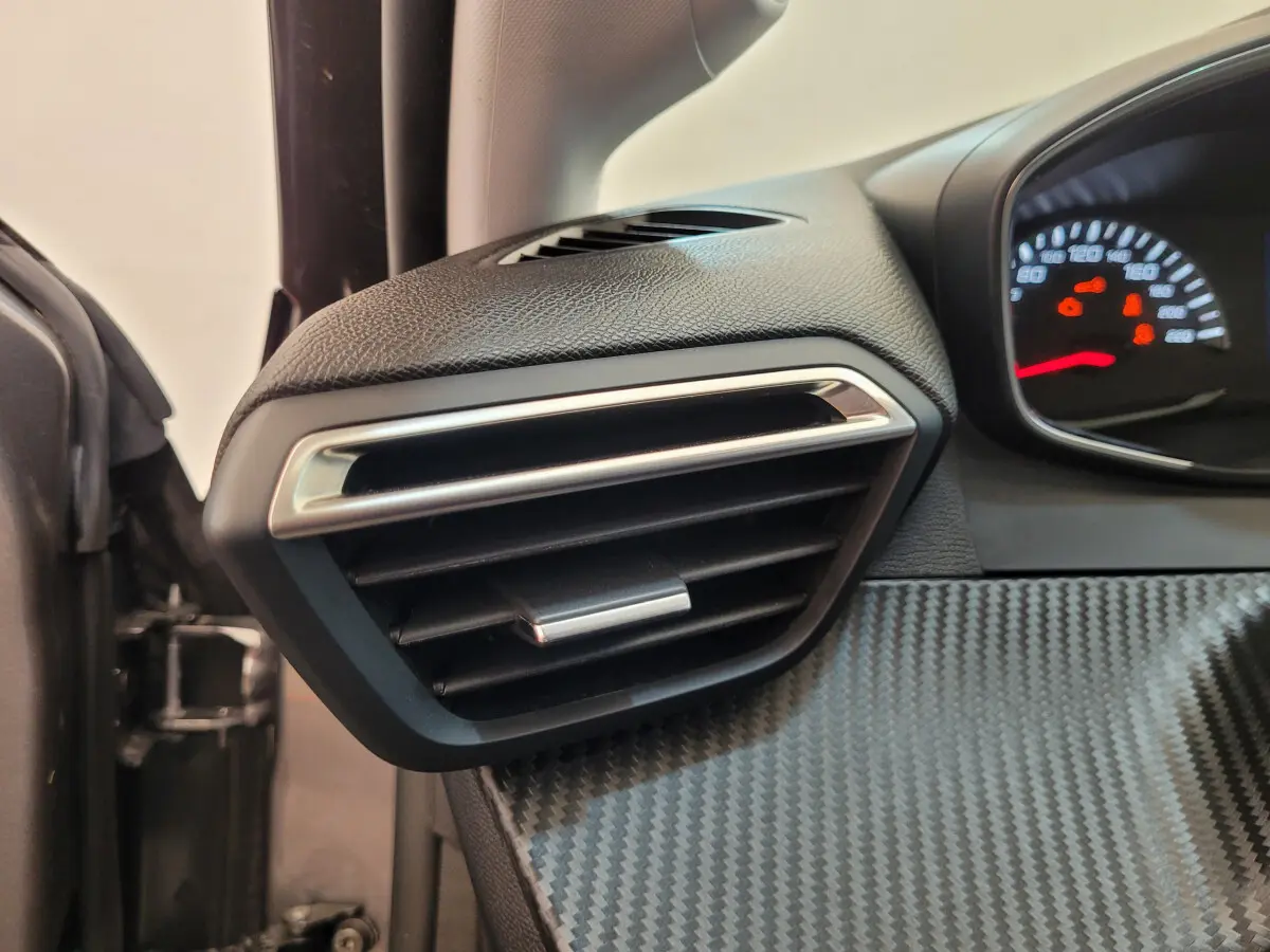 Détail de la sortie d'air côté gauche avec tableau de bord effet carbone du Peugeot 208 gris foncé 2023.