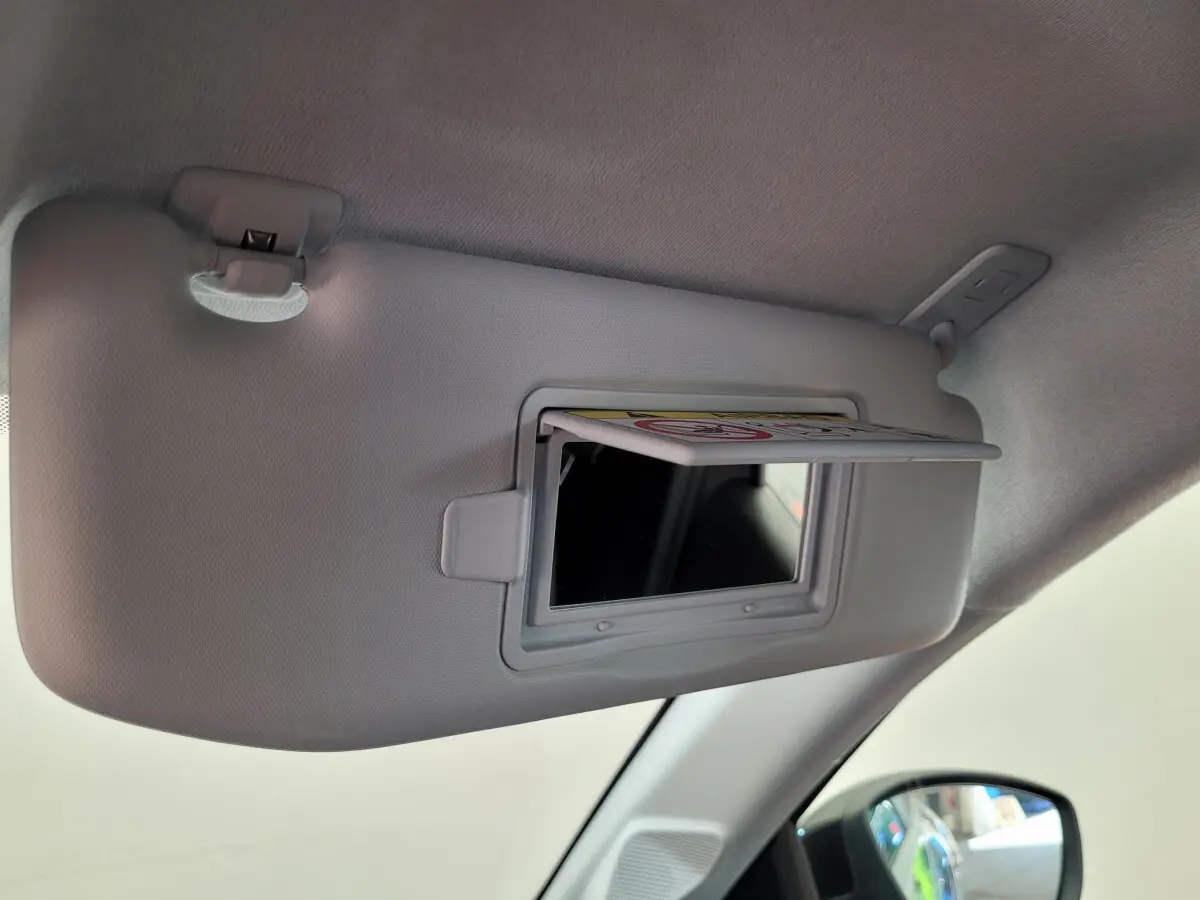 Miroir de courtoisie ouvert sur pare-soleil côté conducteur dans l'habitacle gris clair d'une Peugeot 208 2023.