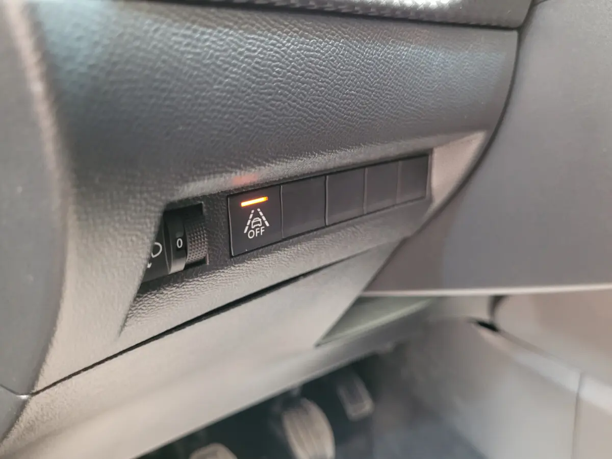 Gros plan sur le tableau de bord côté conducteur de la Peugeot 208 gris foncé, bouton d'alerte de franchissement de ligne activé.