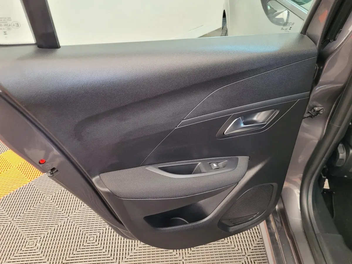 Gros plan sur la porte arrière droite gris foncé de la Peugeot 208 BlueHDi 100 S&S Active Pack avec commande de vitre et haut-parleur intégré.