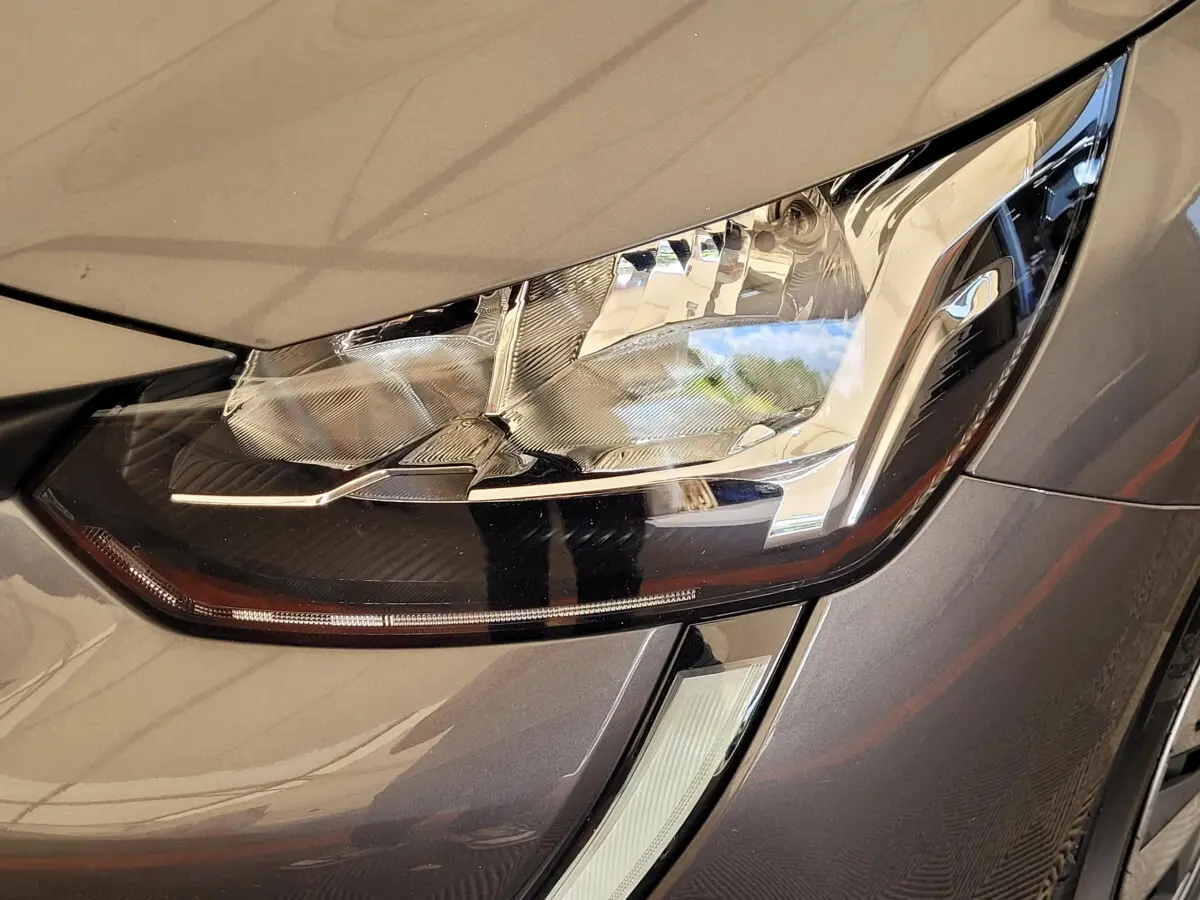 Gros plan sur le phare avant droit gris foncé de la Peugeot 208 BlueHDi 100 S&S Active Pack 2023.