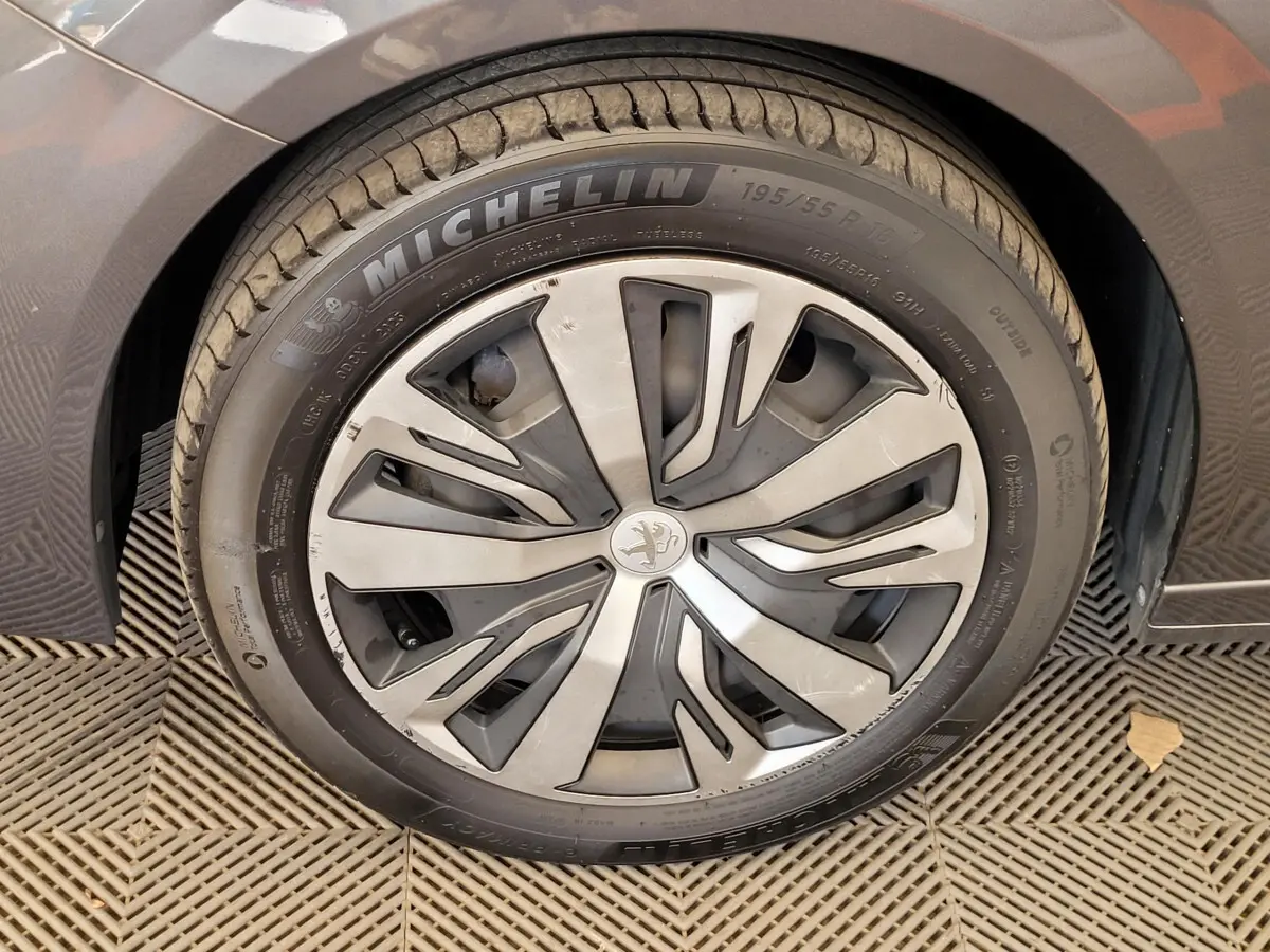 Gros plan sur la roue avant gauche d'une Peugeot 208 gris foncé avec jante alliage et pneu Michelin.