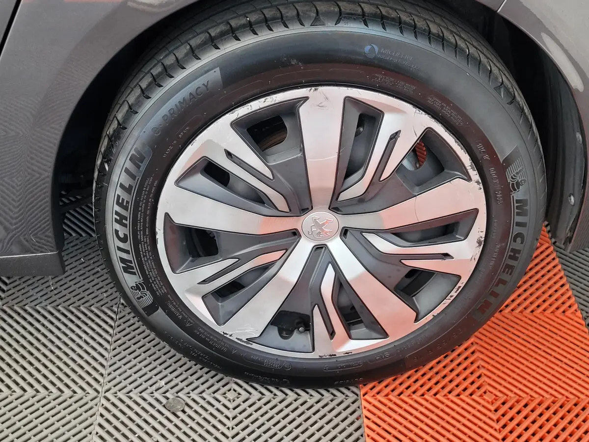 Gros plan sur la roue avant droite d'une Peugeot 208 gris foncé avec jante en alliage et pneu Michelin.