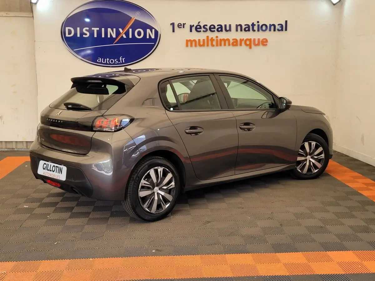 Peugeot 208 gris foncé vue 3/4 arrière droit en intérieur avec jantes alliage et feux LED distinctifs.