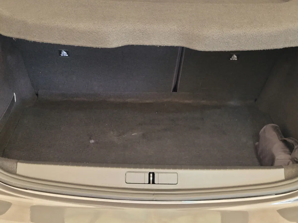 Coffre ouvert d'une Peugeot 208 gris foncé 2023, vue arrière montrant l'espace de chargement vide.