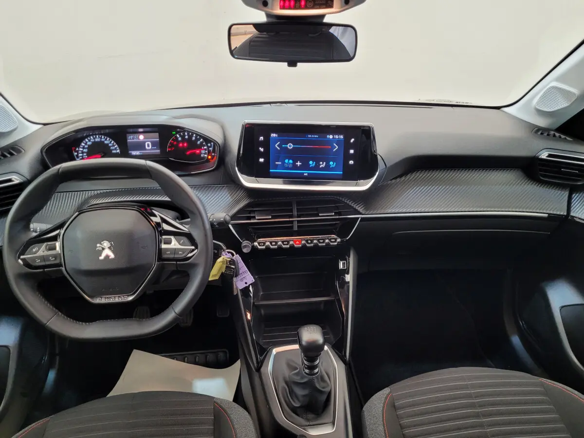 Vue intérieure avant du tableau de bord et volant cuir noir de la Peugeot 208 gris foncé avec écran tactile central.