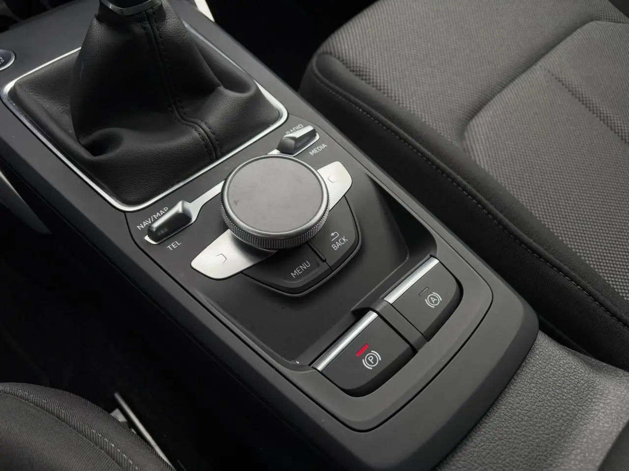 Gros plan sur la console centrale noire de l'Audi Q2 30 TFSI S-Line avec commande MMI et levier de vitesse manuel.