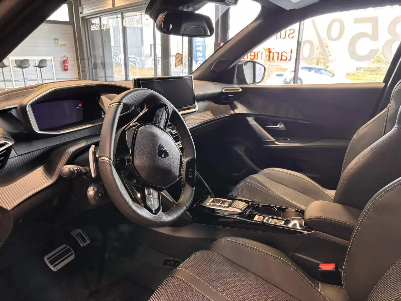 Intérieur du Peugeot 2008 gris 2025, vue côté conducteur, volant multifonction et écran central moderne.