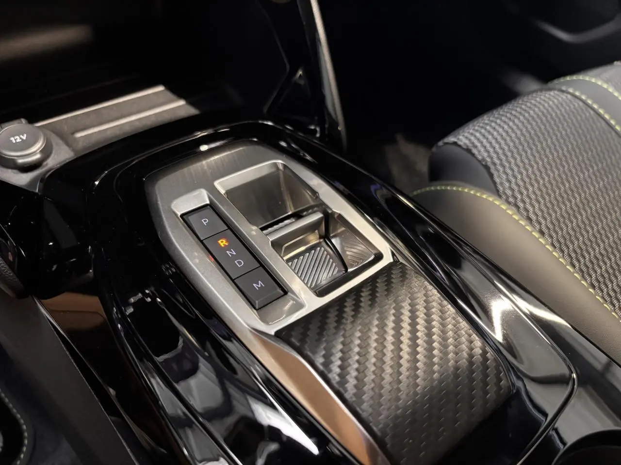 Gros plan sur la console centrale du Peugeot 2008 gris, mettant en valeur la boîte automatique et les surpiqûres vertes des sièges.