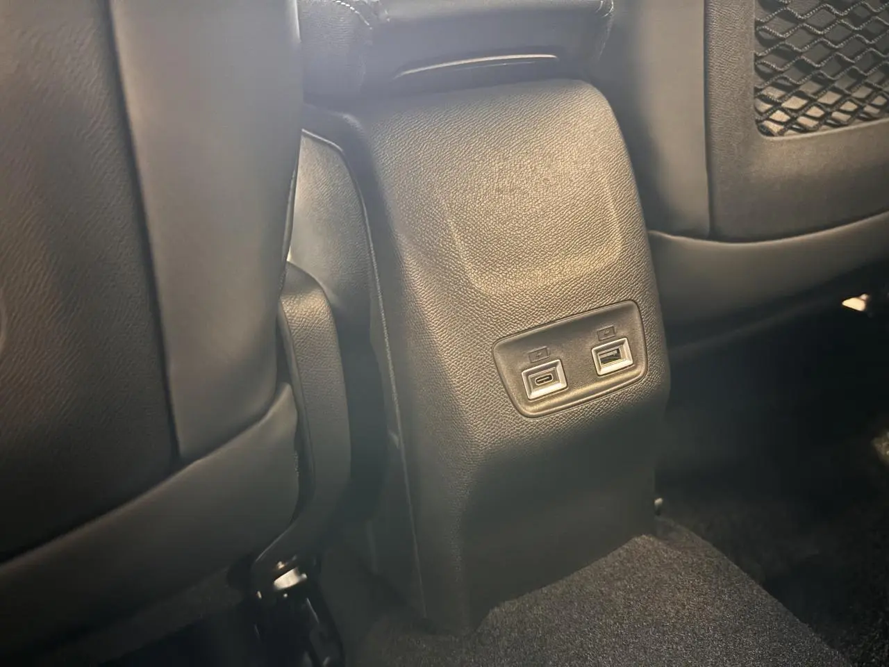 Prise USB arrière double sur console centrale noire, entre les sièges avant du Peugeot 2008 gris hybride 2025.