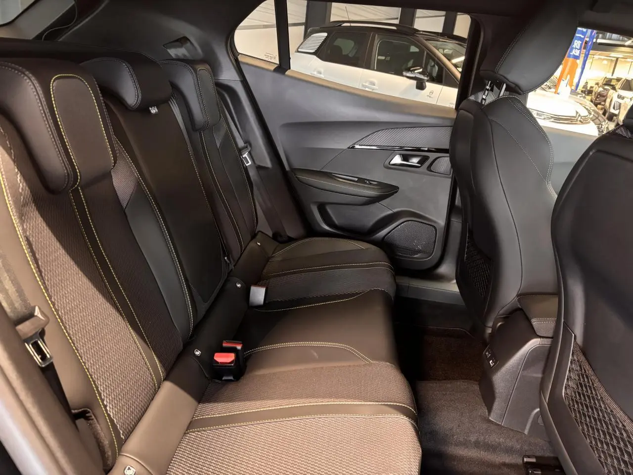 Vue intérieure côté droit sur les sièges arrière noirs avec surpiqûres jaunes du Peugeot 2008 gris hybride 2025.