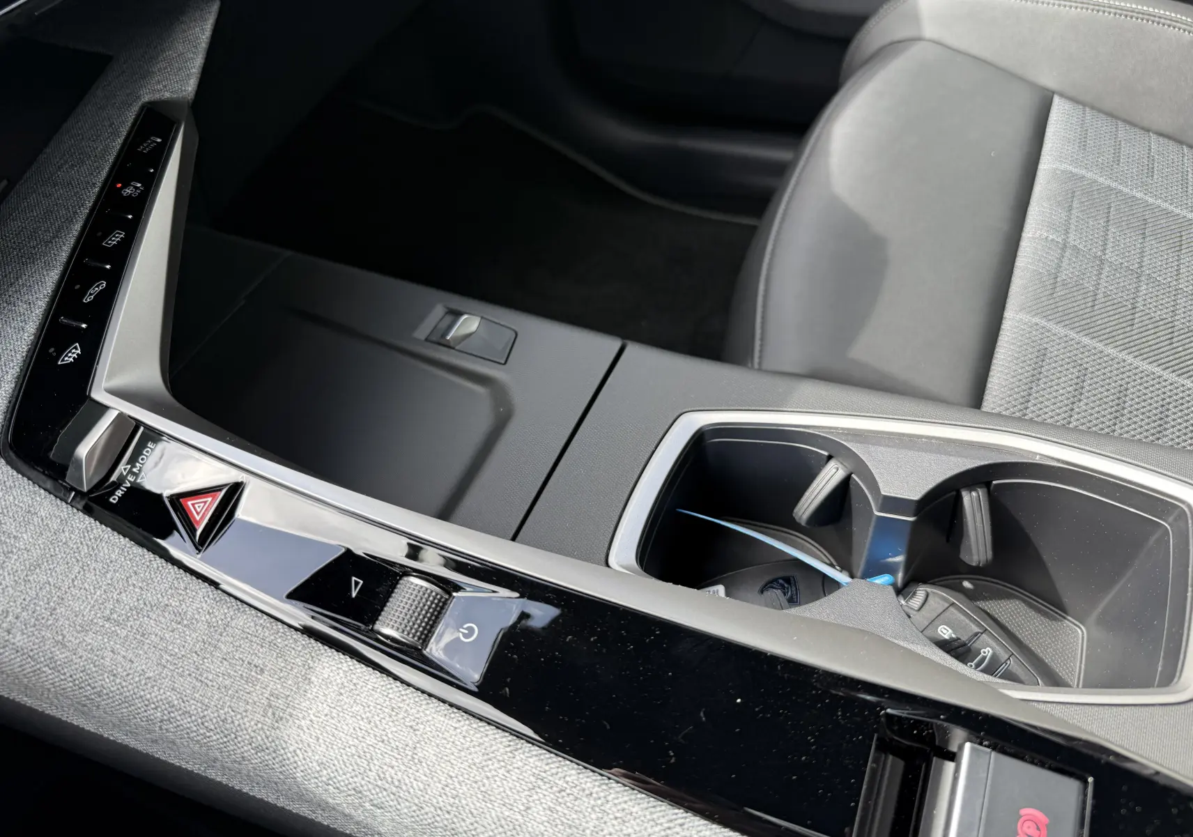 Gros plan sur la console centrale noire du Peugeot 3008 Hybrid 2026 avec porte-gobelets et commandes tactiles.