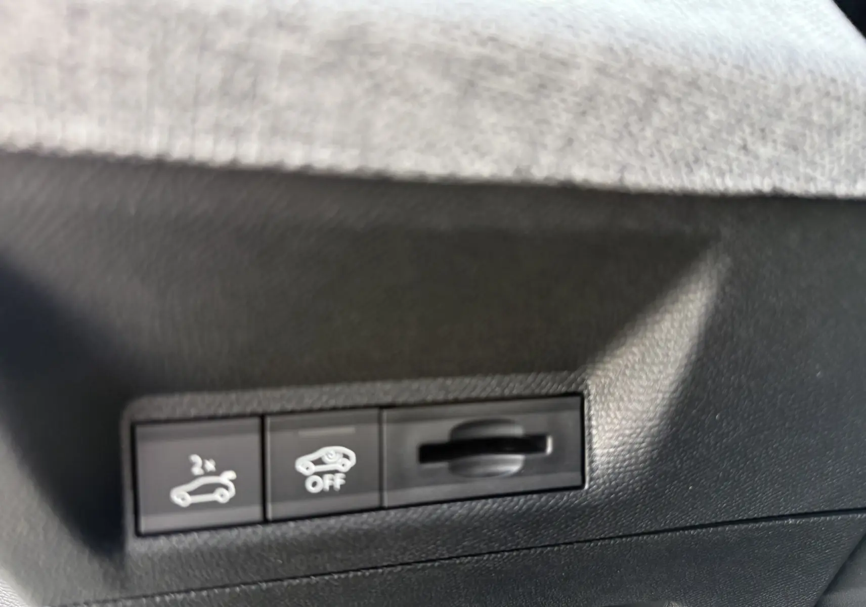 Détail intérieur des commandes noires sous tableau de bord du Peugeot 3008 Hybrid blanc, avec boutons hayon et assistance désactivée.