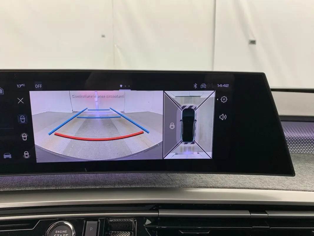 Coffre ouvert vu de l'arrière d'un Peugeot 3008 Hybrid blanc avec intérieur de coffre noir et cache-bagages relevé.