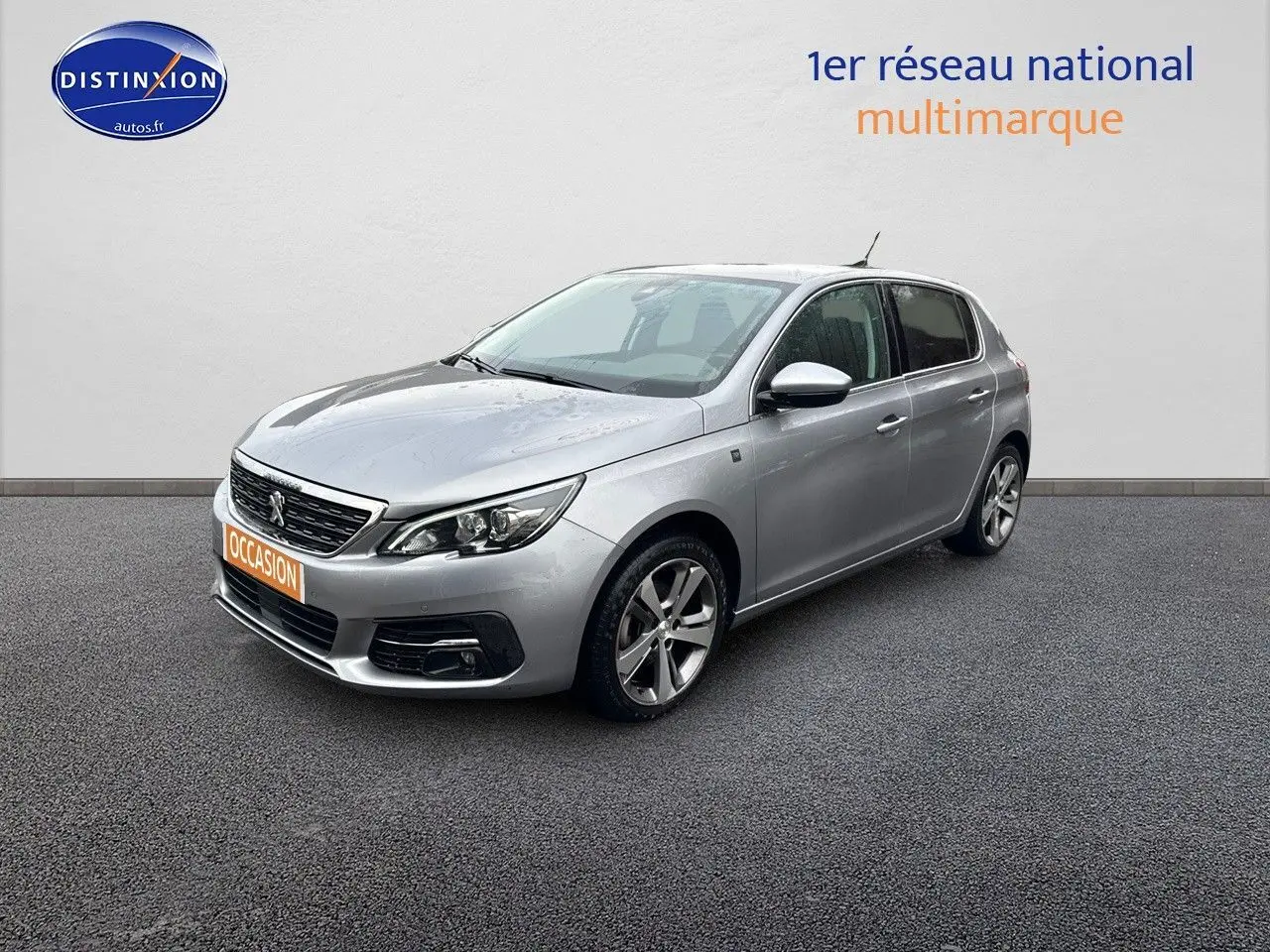 Peugeot 308 gris Artense vue 3/4 avant droit, avec jantes alliage et calandre noire brillante.