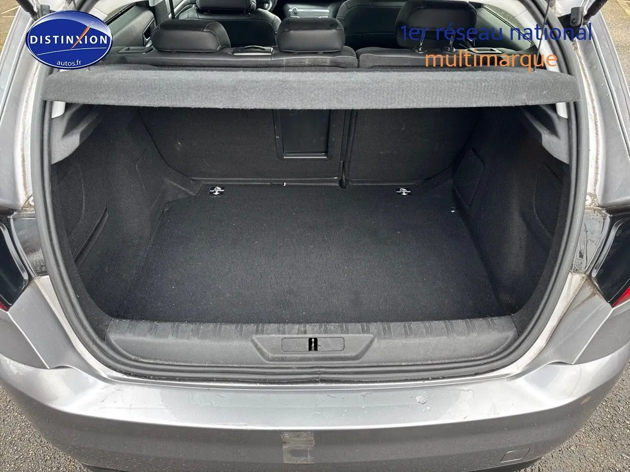 Coffre ouvert d'une Peugeot 308 gris Artense vue de l'arrière, montrant un espace de chargement propre et spacieux.