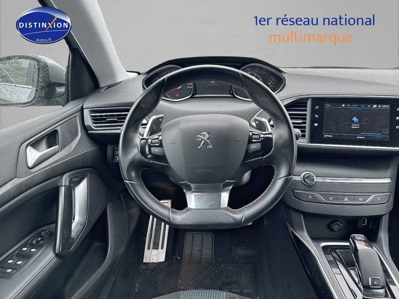 Vue intérieure centrée sur le volant cuir de la Peugeot 308 gris Artense avec tableau de bord et écran tactile.