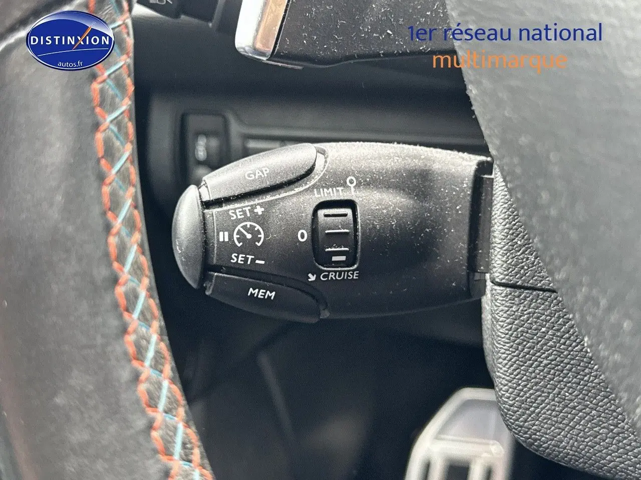 Gros plan sur la commande de régulateur de vitesse au volant d'une Peugeot 308 gris Artense de 2019.