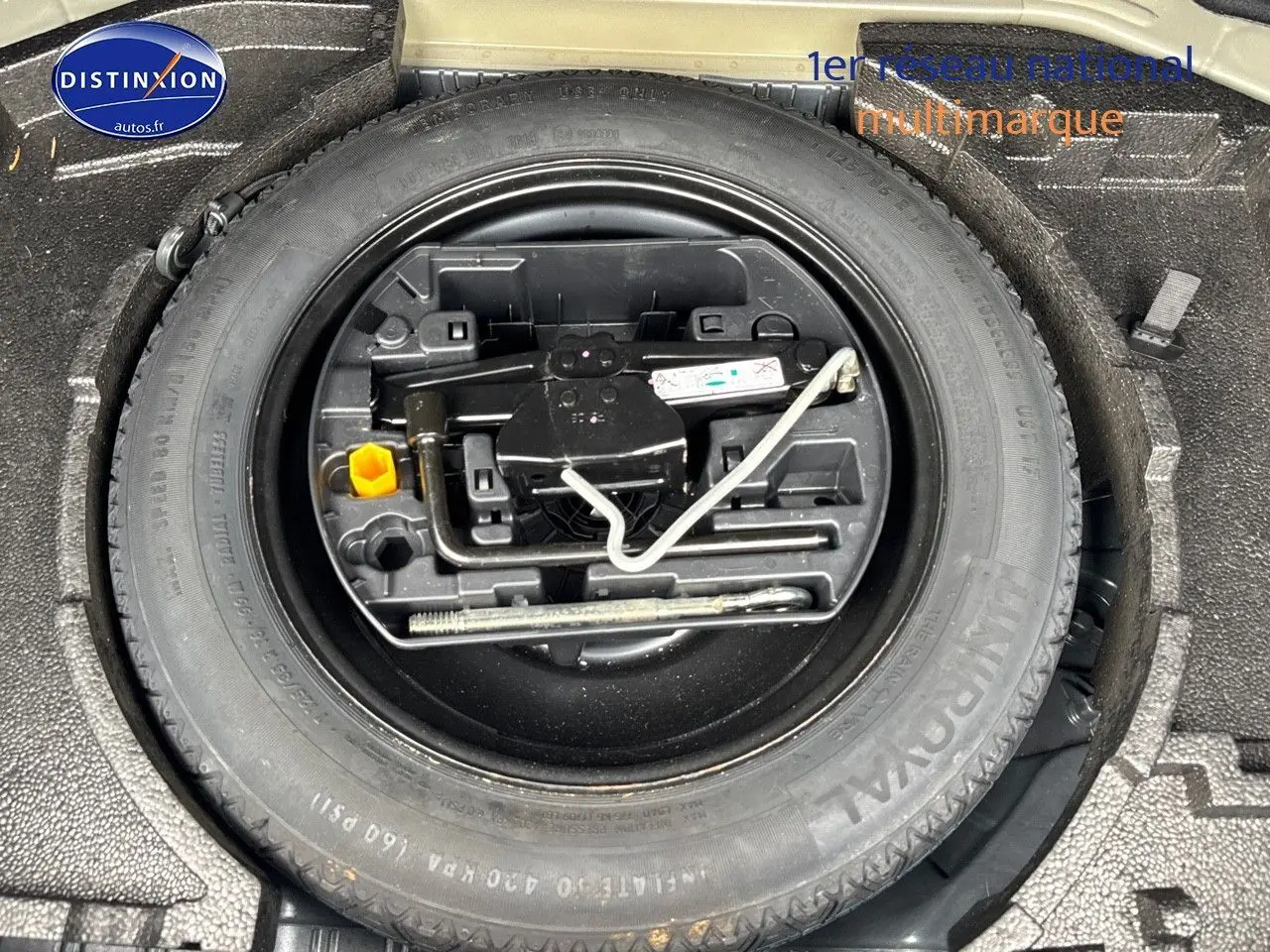 Roue de secours et outils de bord rangés dans le coffre d'une Peugeot 308 gris Artense de 2019.