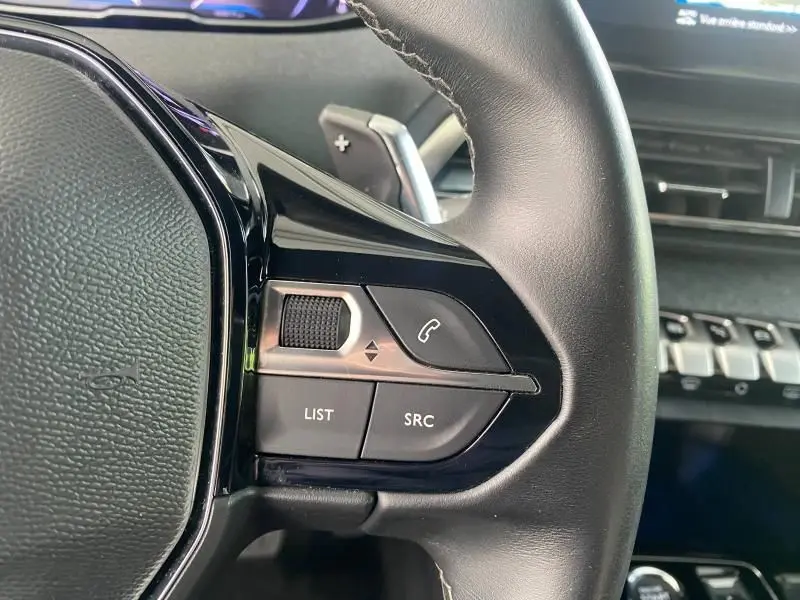 Gros plan sur les commandes audio et téléphone au volant cuir noir du Peugeot 3008 blanc nacré 2023.