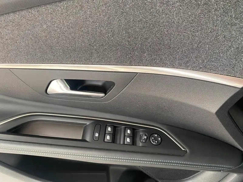 Détail de la porte côté gauche d'une Peugeot 3008 blanc nacré, avec commandes électriques des vitres et rétroviseurs.