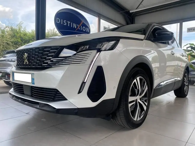 Peugeot 3008 blanc nacré vue 3/4 avant droit en showroom, avec calandre noire et phares LED distinctifs.