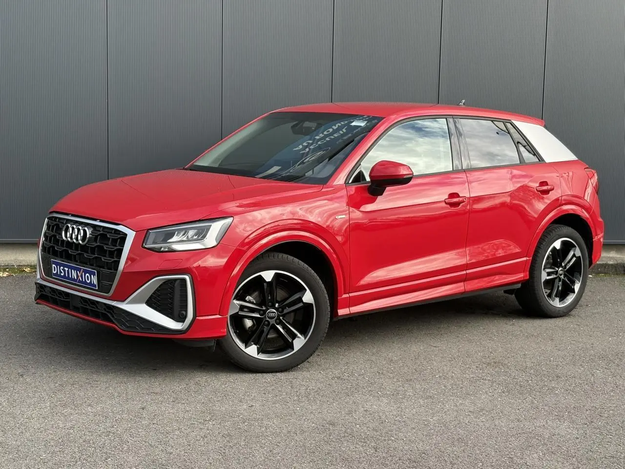 Audi Q2 30 TFSI S-Line rouge progressif vue 3/4 avant droit avec toit blanc et jantes alliage noir poli.