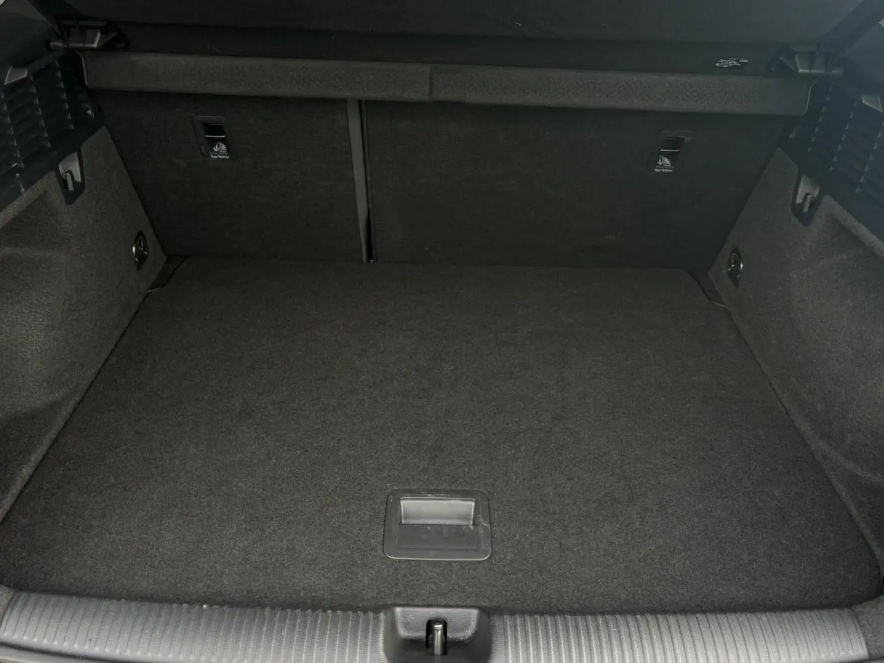 Vue intérieure du coffre spacieux et vide de l'Audi Q2 30 TFSI S-Line, avec revêtement noir uniforme.