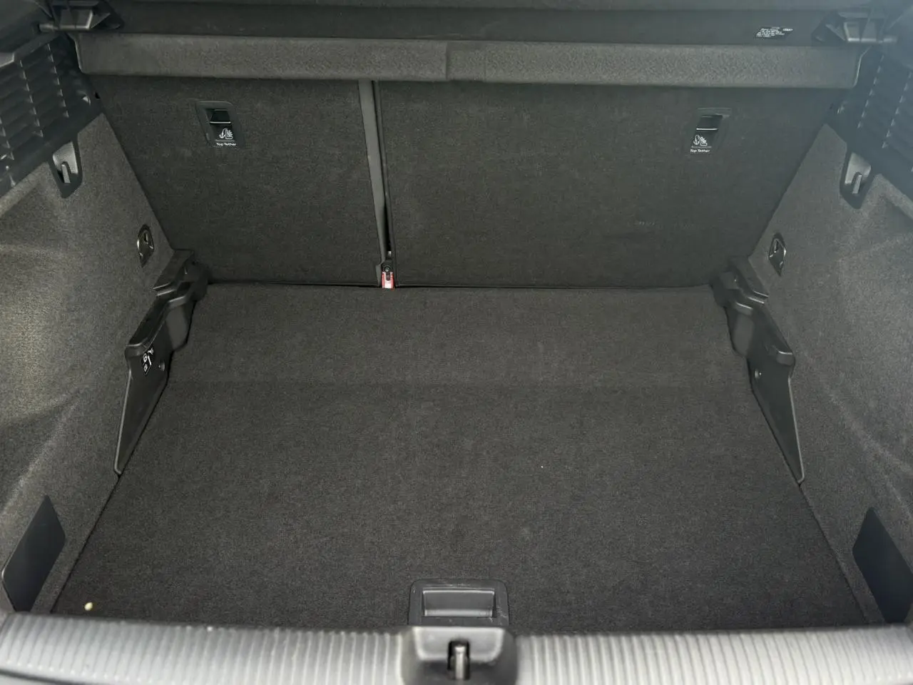 Coffre ouvert de l'Audi Q2 30 TFSI S-Line 2024, vue intérieure arrière montrant un espace de chargement noir.