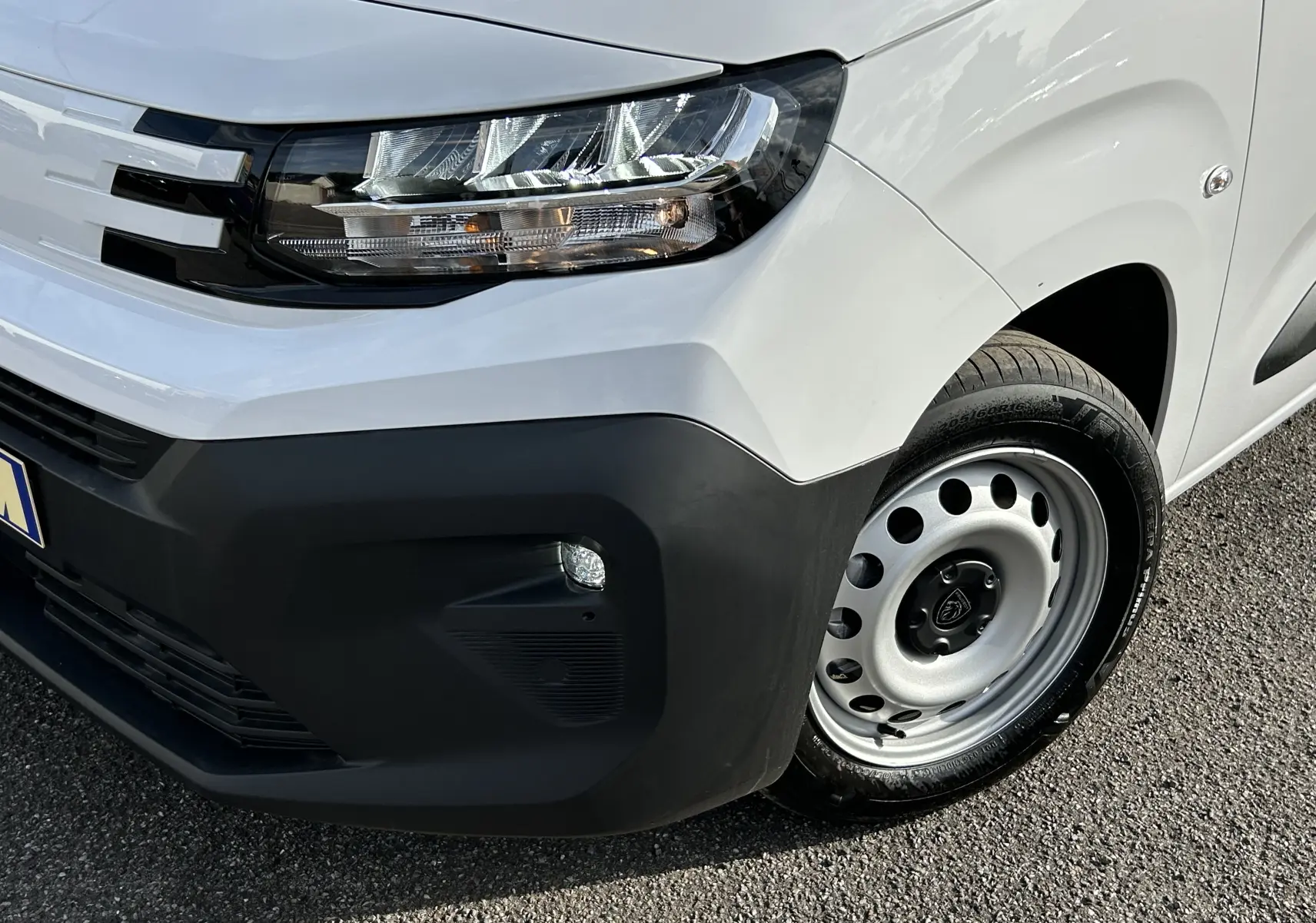 Gros plan sur l'avant droit blanc du Peugeot Partner Fourgon avec phare LED et jante acier simple.