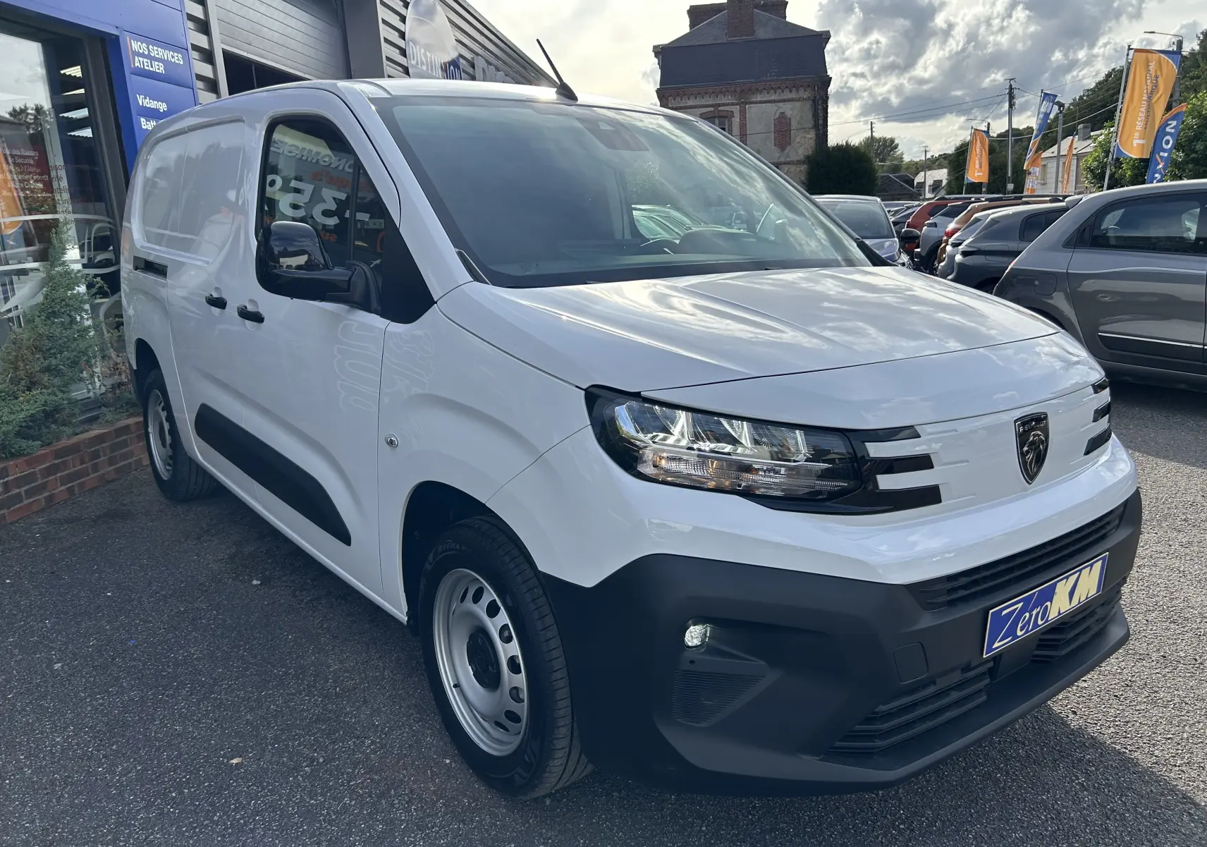Vue 3/4 avant d'un Peugeot Partner Fourgon blanc avec rétroviseurs noirs et pare-chocs avant noir mat.